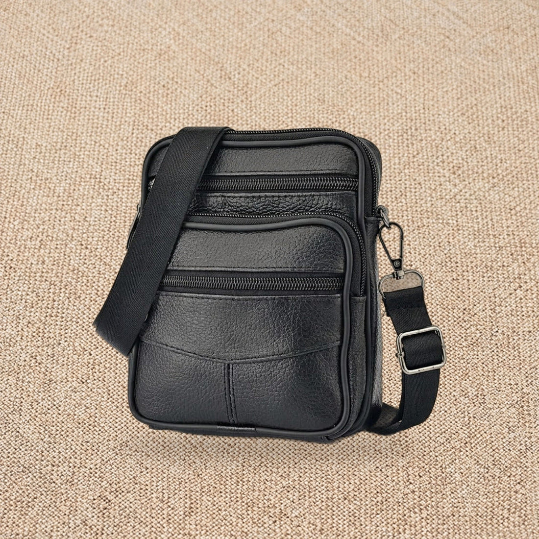 Sacoche bandoulière homme en cuir Le Compagnon, coloris noir, vue de face sur un fond de lin beige